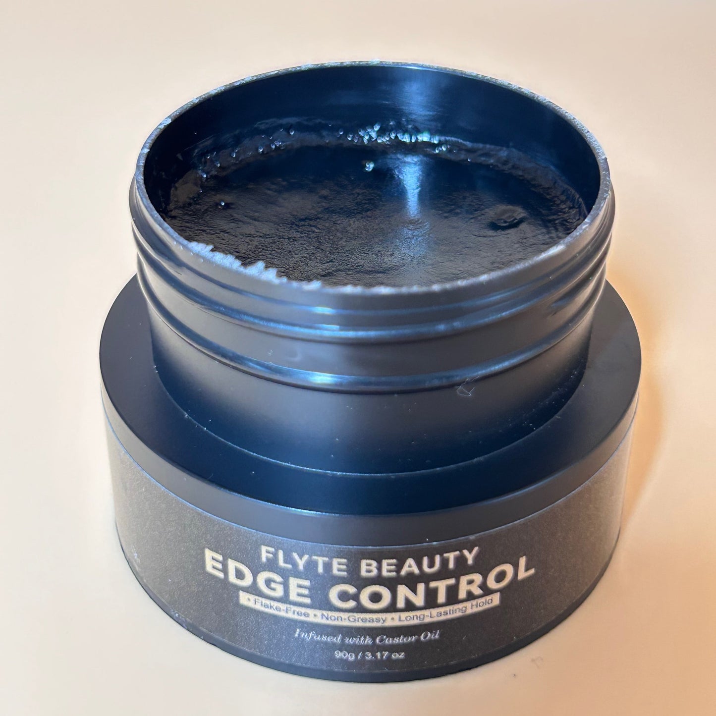 Blue jar of Flyte Beauty Edge Control on a light background