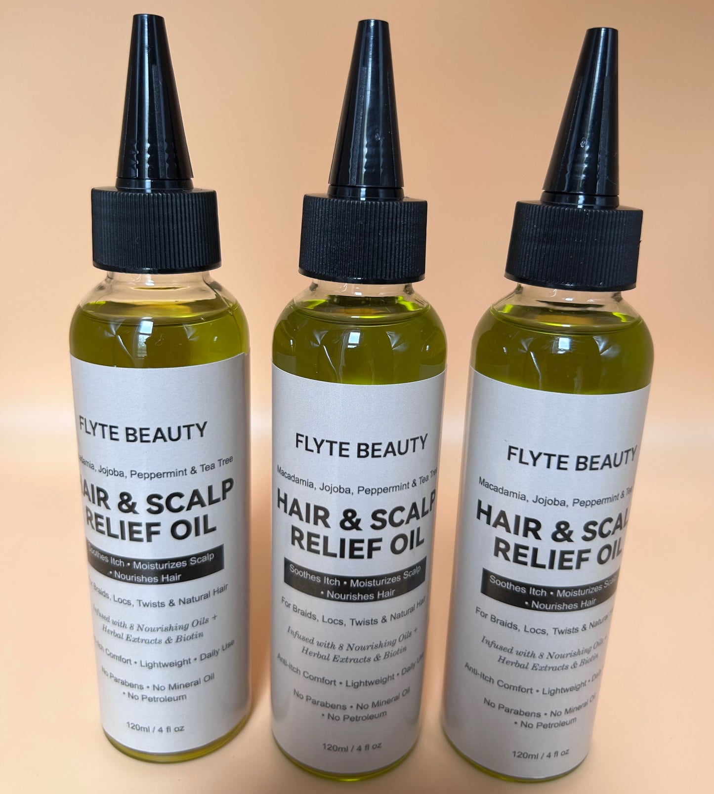 Three bottles of Flyte Beauty Hair & Scalp Relief Oil on a beige background