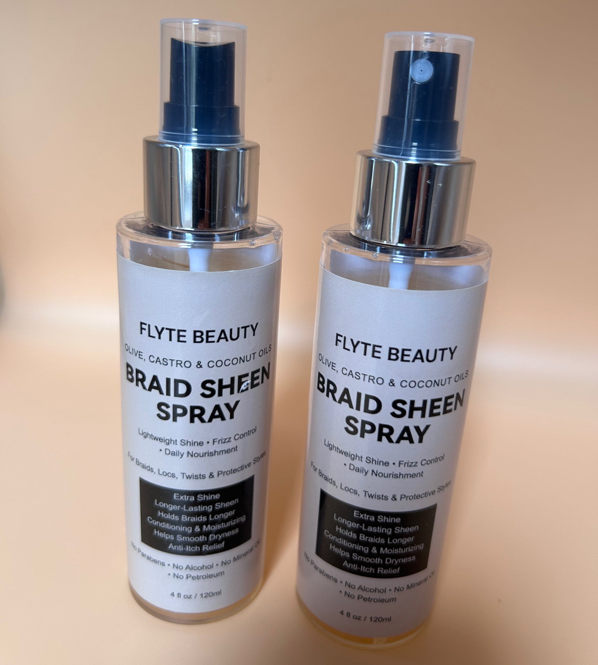 Two bottles of Flyte Beauty Braid Sheen Spray on a beige background