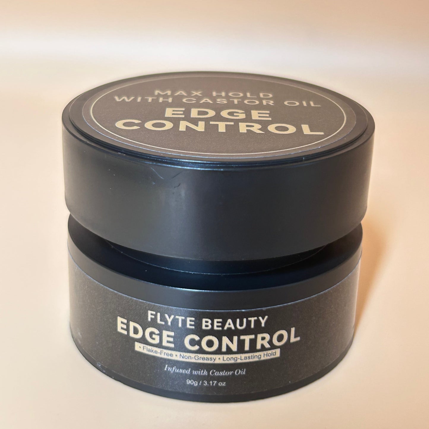 Black jar of Flyte Beauty Edge Control on a beige background